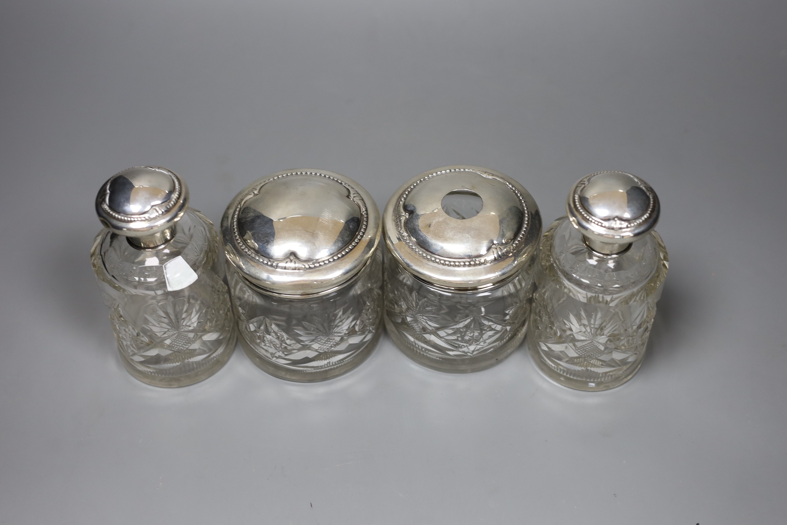 A pair of Continental white metal mounted cut glass scent bottles, 12.5cm and two matching toilet jars
